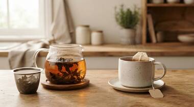 Loose leaf tea brewing beside a simple teabag cup in morning light