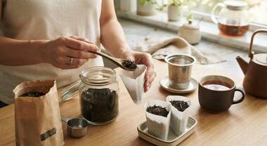 Loose tea being portioned into paper filters for convenient brewing